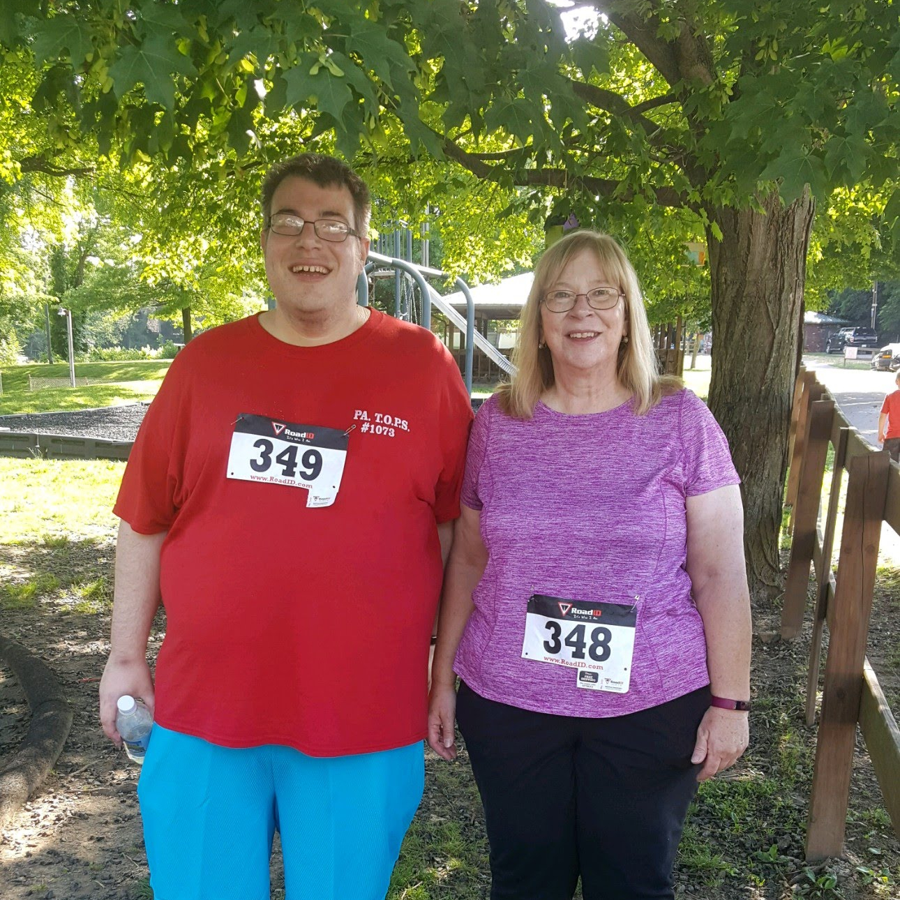 Me wearing a Red tshirt and teal shorts standing next to my mother who is wearing a purple top and black pants after walking a 5K race on my 36th birthday.
